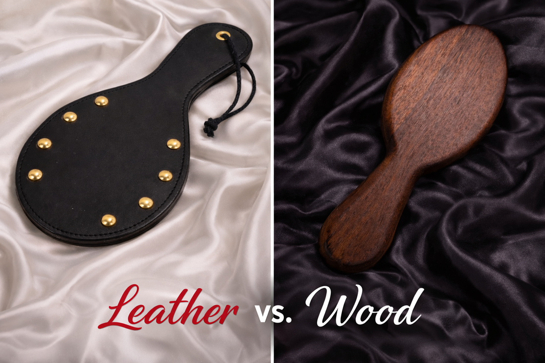 Side-by-side comparison of a black leather paddle with brass studs on white silk and a wooden paddle on black silk, titled “Leather vs. Wood”.